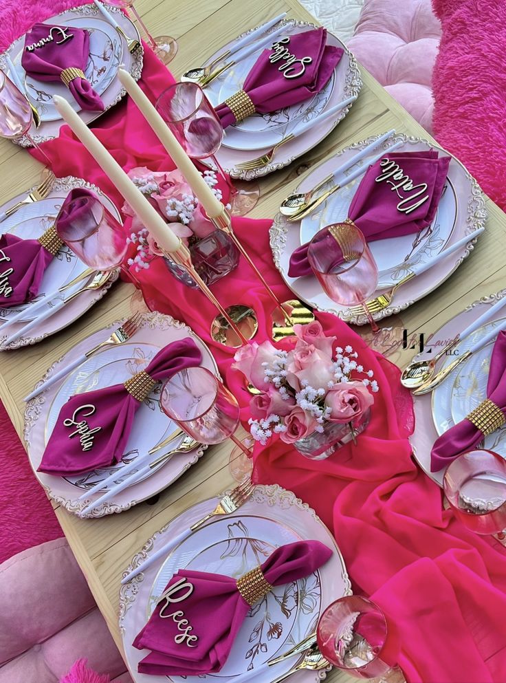 the table is set with pink napkins and place settings