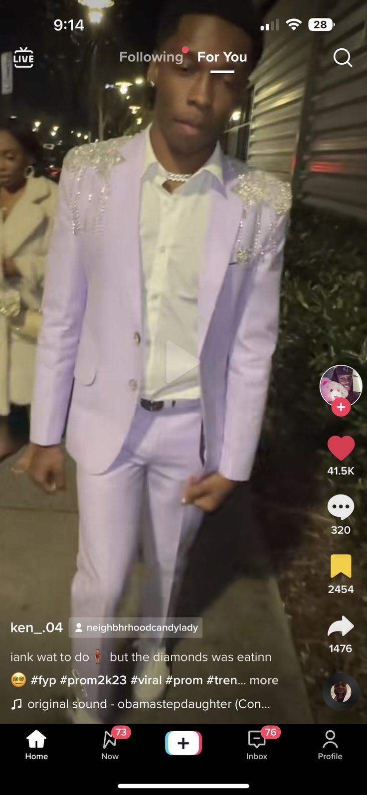 a man in a pink suit and white shirt is walking down the street at night