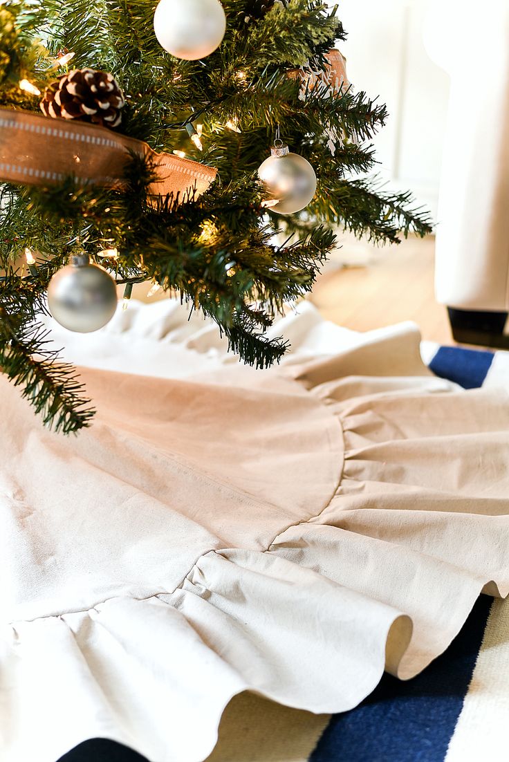 a small christmas tree with white and silver ornaments