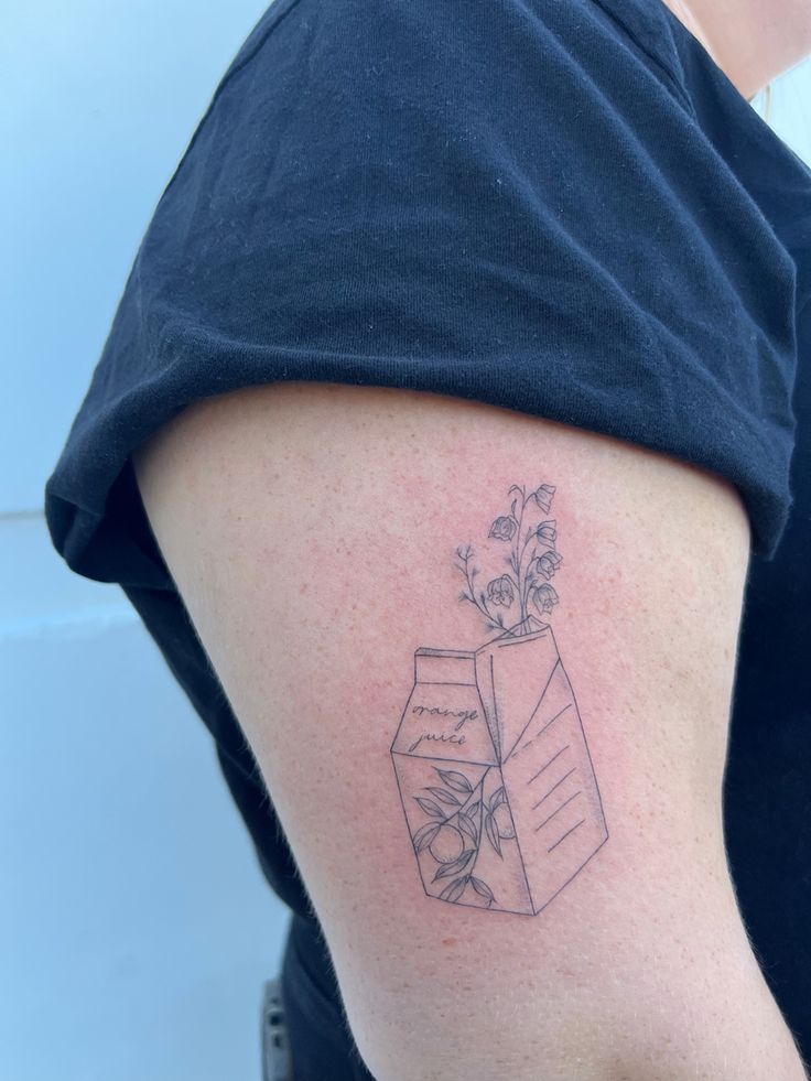 a woman with a tattoo on her arm has a flower in a vase behind it