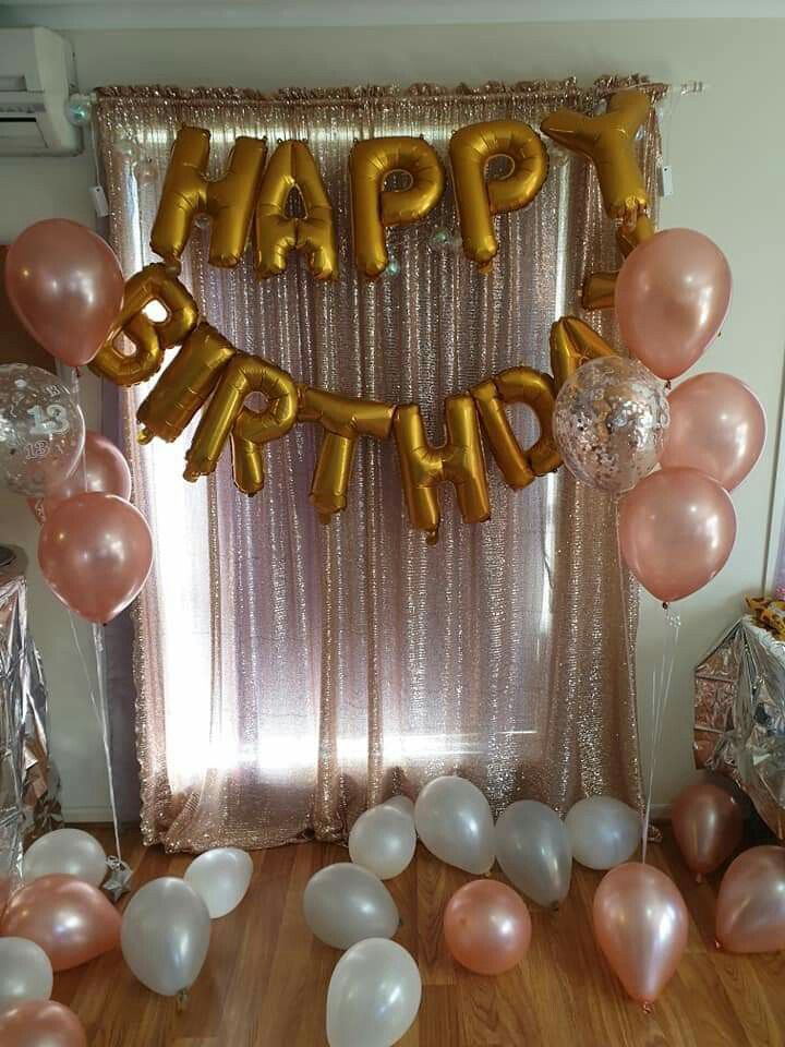 balloons and streamers in front of a happy birthday balloon arch on a wooden floor