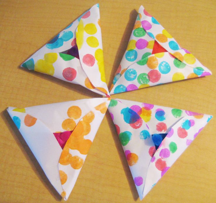 four pieces of paper are arranged in the shape of three triangles with colorful dots on them