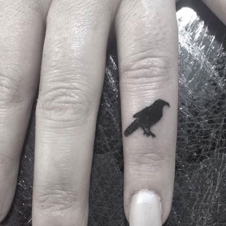 a person with a bird tattoo on their finger