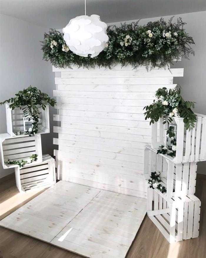 a room with white walls and plants on the wall, some chairs and a light fixture