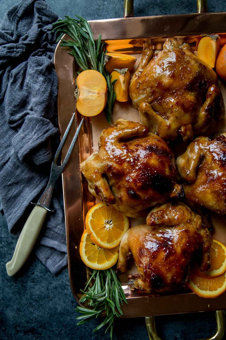 a roasting pan filled with chicken, oranges and carrots