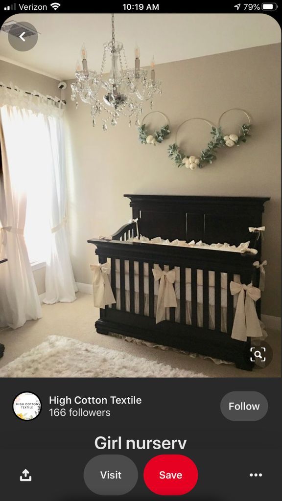 a baby crib in a room with curtains and chandelier