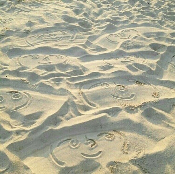 smiley faces drawn in the sand at the beach