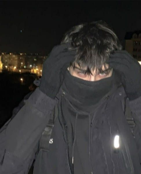 a man covering his face with both hands while standing in front of a city at night