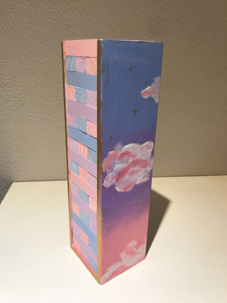 a tall pink and blue vase sitting on top of a white table next to a wall