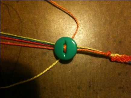 a close up of a string with a green button on it