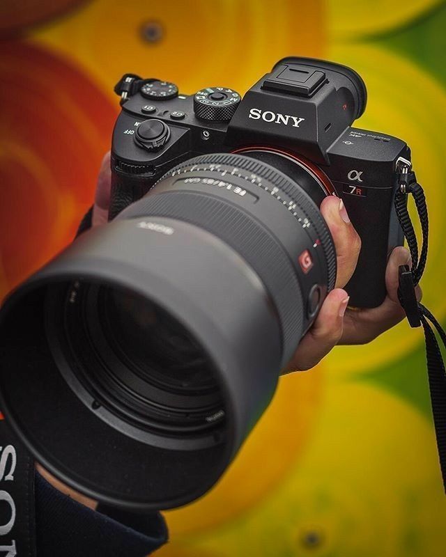 a person holding a camera in front of a colorful background