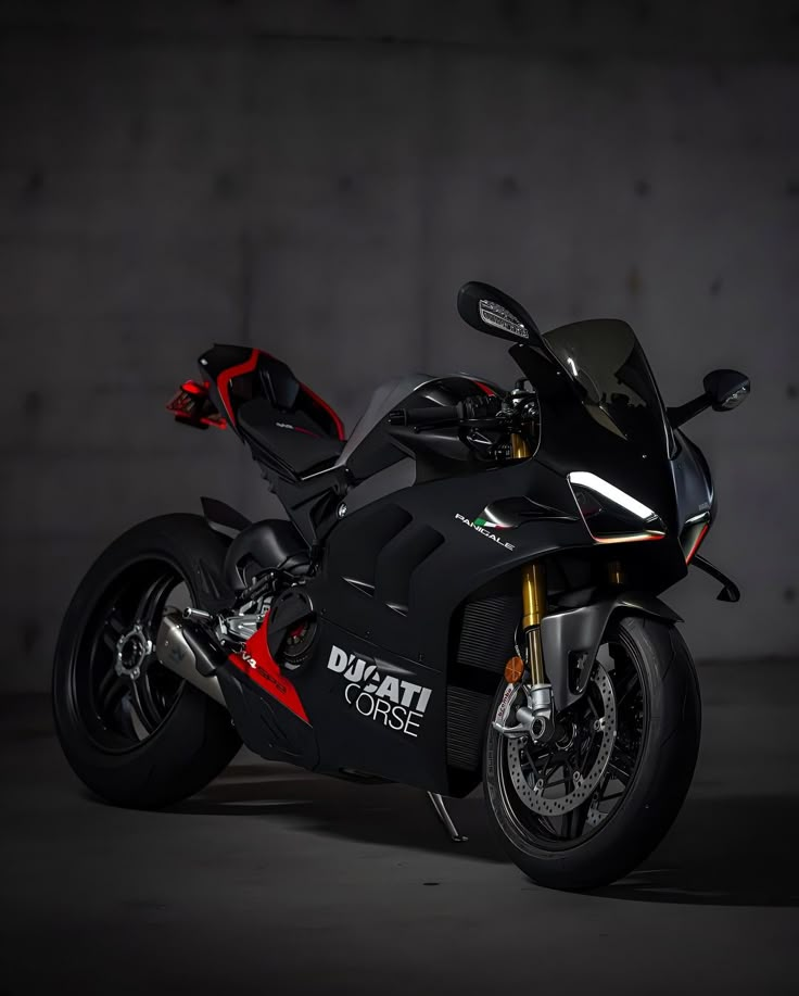 a black and red motorcycle is parked in a dark area with concrete walls behind it