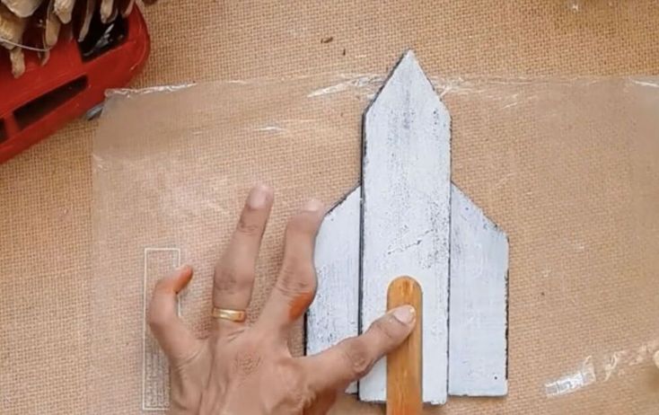 a person's hand on top of a piece of wood