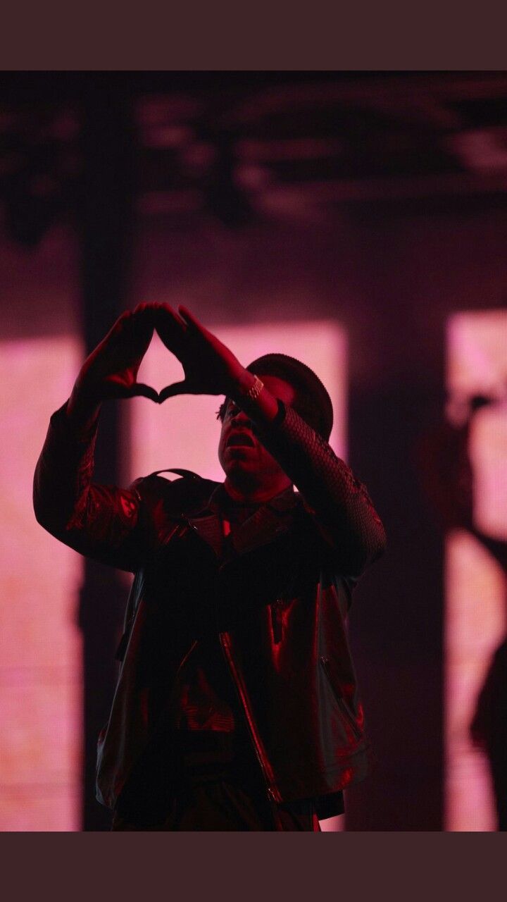 a man making a heart with his hands in front of the shadow of another person