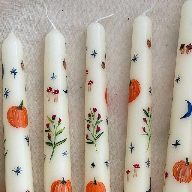 four white candles decorated with pumpkins and stars