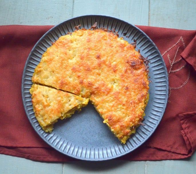 a piece of quiche on a blue plate with a red napkin next to it