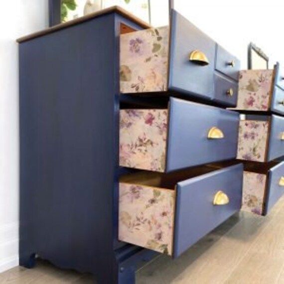 a blue dresser with floral drawers on it