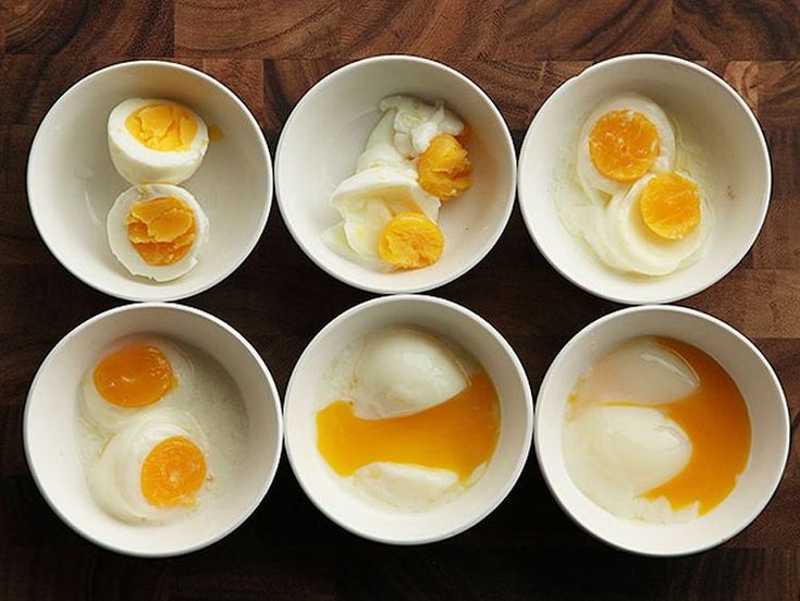 six bowls filled with eggs on top of a wooden table next to an orange peel