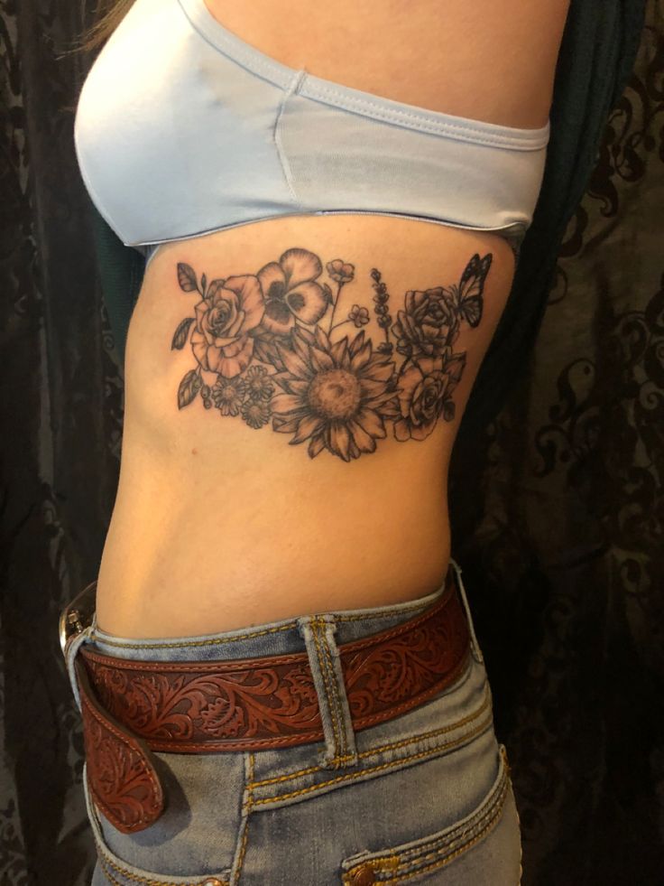 a woman's stomach with flowers on it and a cowboy belt around her waist