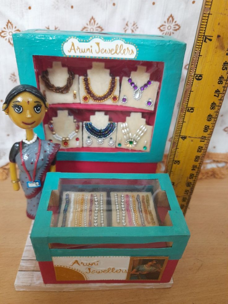 a doll is standing next to a box with jewelry in it