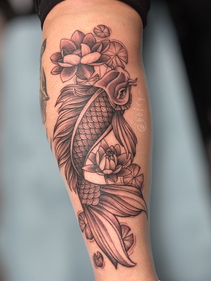 a woman's leg with a koi fish and flowers tattoo design on it