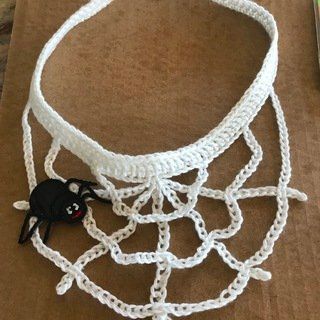 a white crocheted choker with black beads and a spider web on it