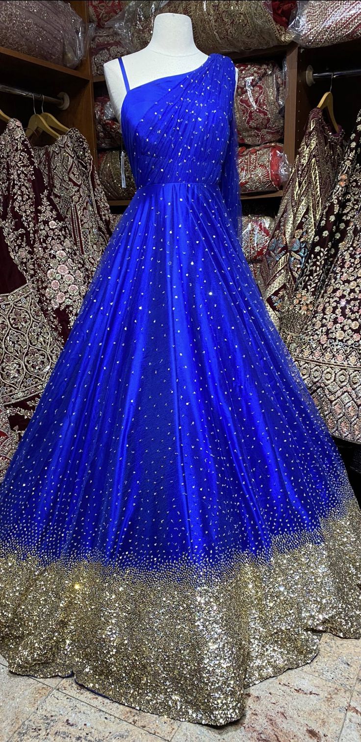 This sparkle blue milky way one-shoulder gown with heavy embellishments with sequin and swaroski work is a contemporary pick with golden sequence border design. Make an grand entry on your special day in this beautiful gown. Fabric: Net Size: 38 Ready to Ship! Glamorous Blue Ball Gown For Wedding, Glamorous Blue Embellished Gown, Blue Gown With Rhinestones For Party, Blue Rhinestone Gown For Prom Season, Glamorous Blue Festive Lehenga, Glamorous Blue Lehenga For Festive Occasions, Blue Glamorous Lehenga For Reception, Blue Sequined Evening Dress For Wedding, Sparkling Blue Evening Dress For Wedding