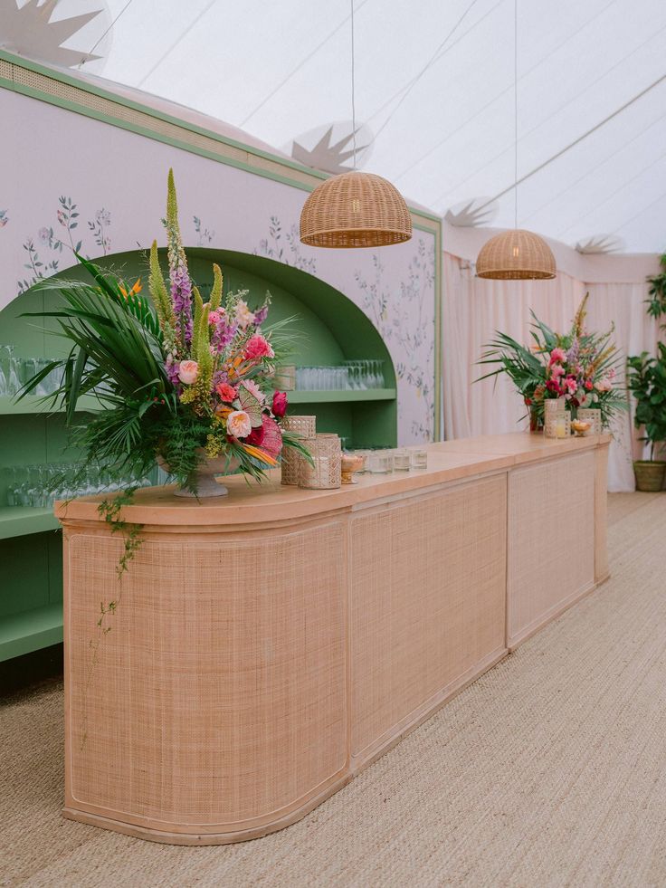 a reception table with flowers and greenery on the counter top in a tented area