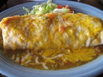 an enchilada is sitting on a plate next to a salad