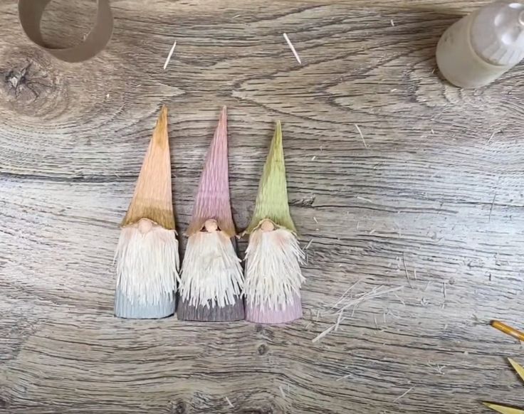 three small gnomes sitting on top of a wooden table next to scissors and pencils