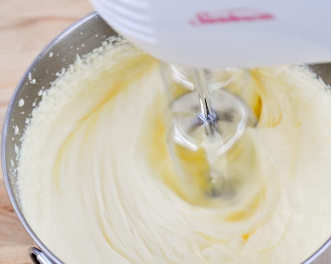 a mixing bowl filled with white batter on top of a wooden table