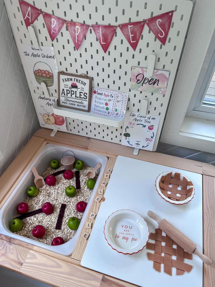 a wooden table topped with bowls and plates filled with food next to a sign that says apples