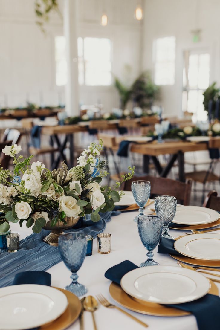 the table is set with blue and white plates, silverware, and floral centerpieces