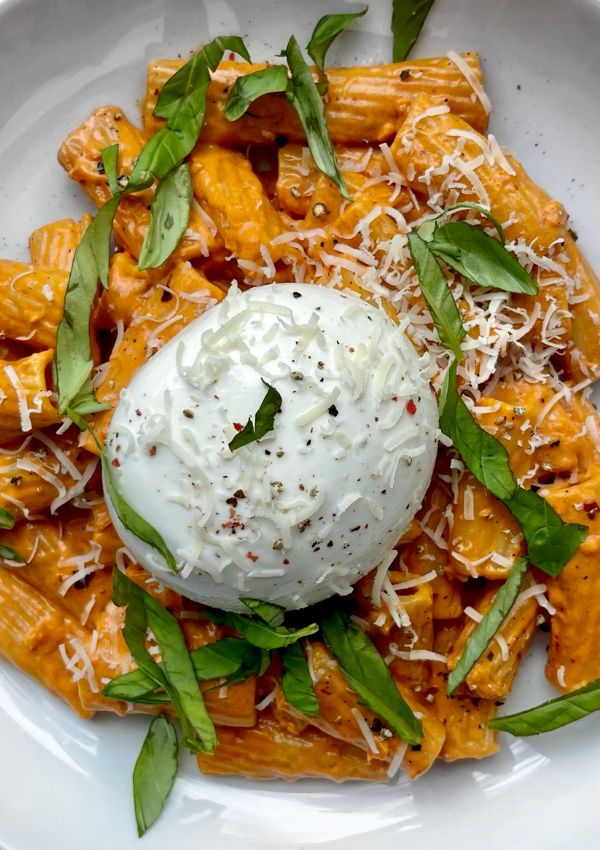 a white plate topped with pasta covered in cheese and spinach garnished with parmesan