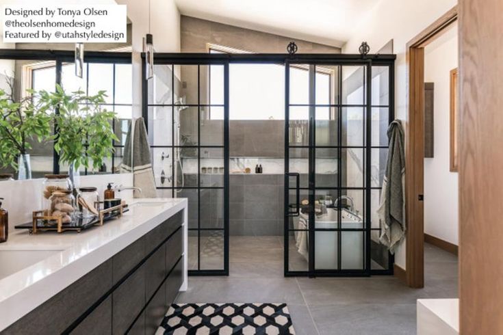 a bathroom with a large mirror, sink and bathtub next to a plant on the counter