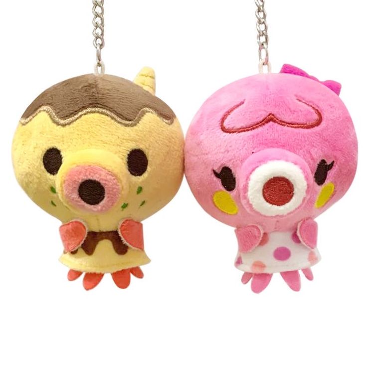 two small stuffed animals hanging from chains on a white background, one is pink and the other is brown