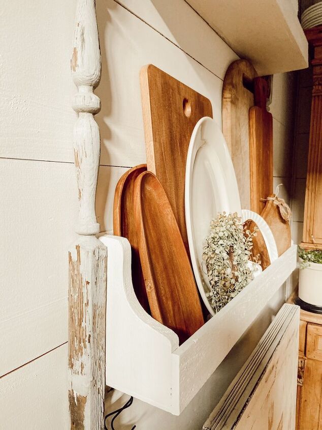 wooden utensils and cutting boards sit in a white shelf on the kitchen counter