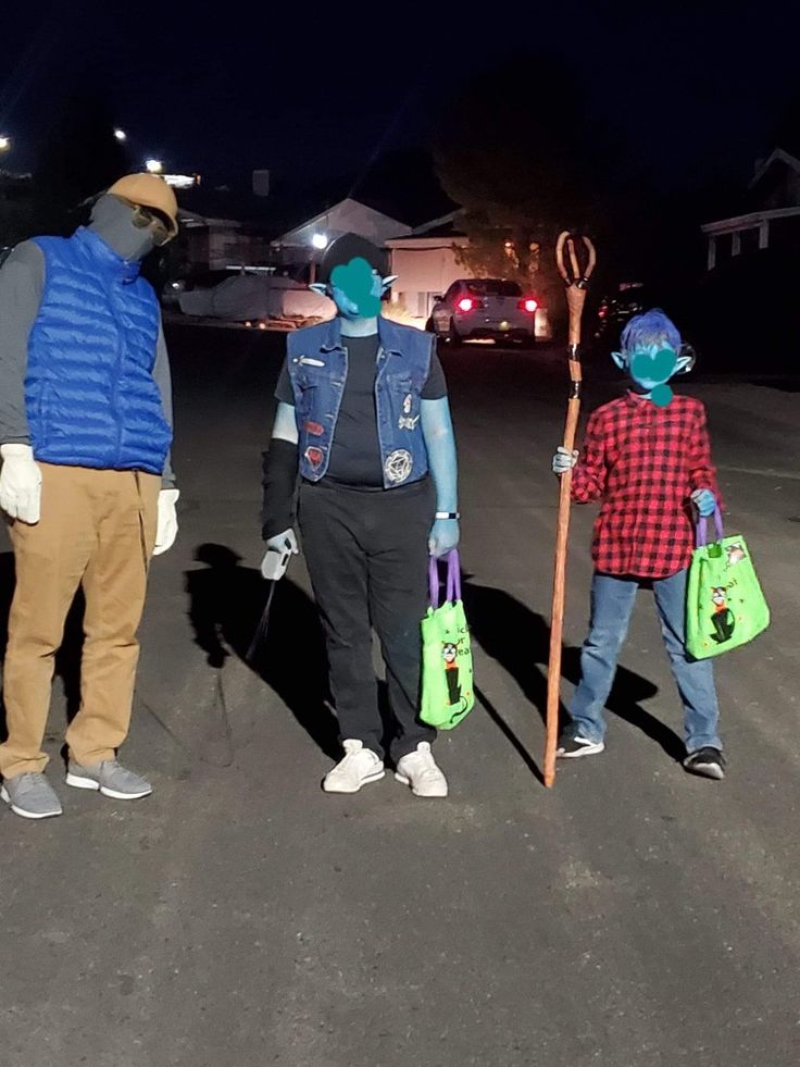 three people standing in the middle of an empty parking lot at night with one person holding a staff