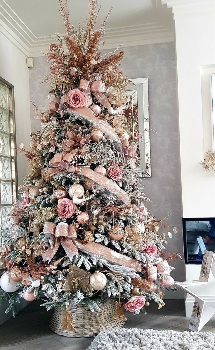 a decorated christmas tree in a living room with pink and gold decorations on the top