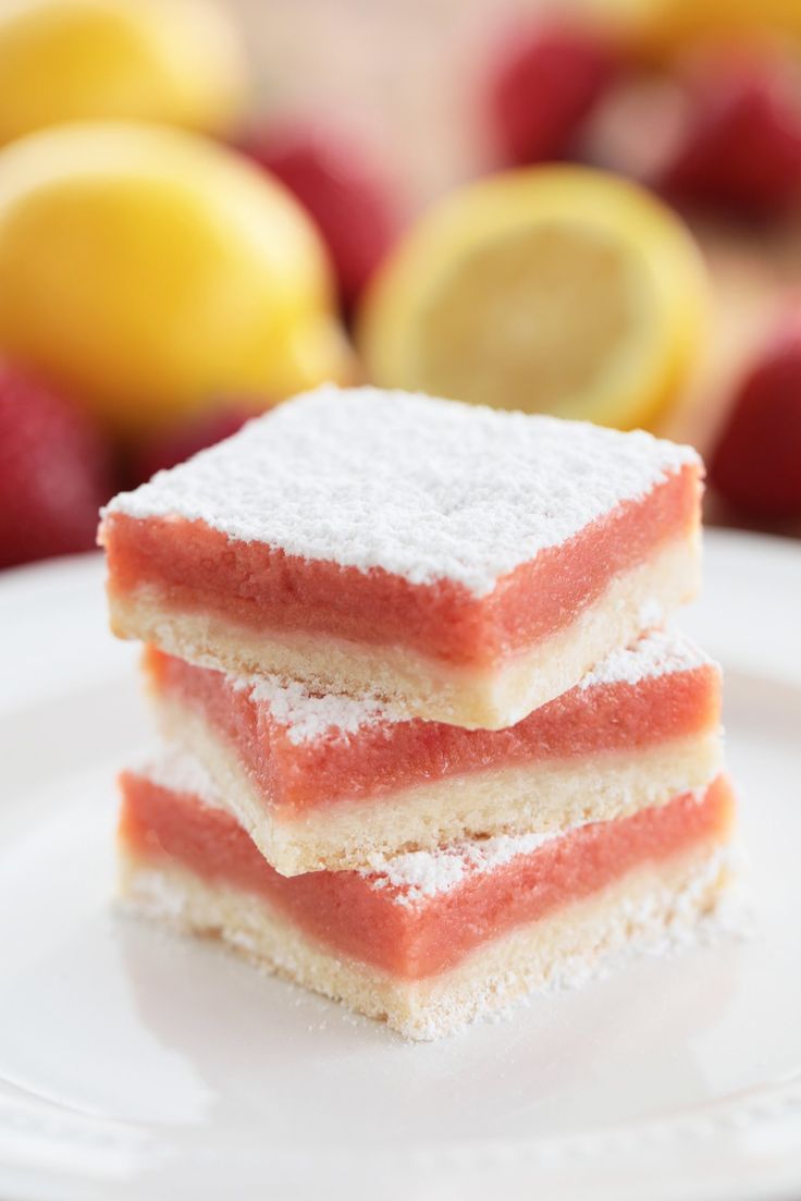 three pieces of cake on a plate with lemons and raspberries in the background