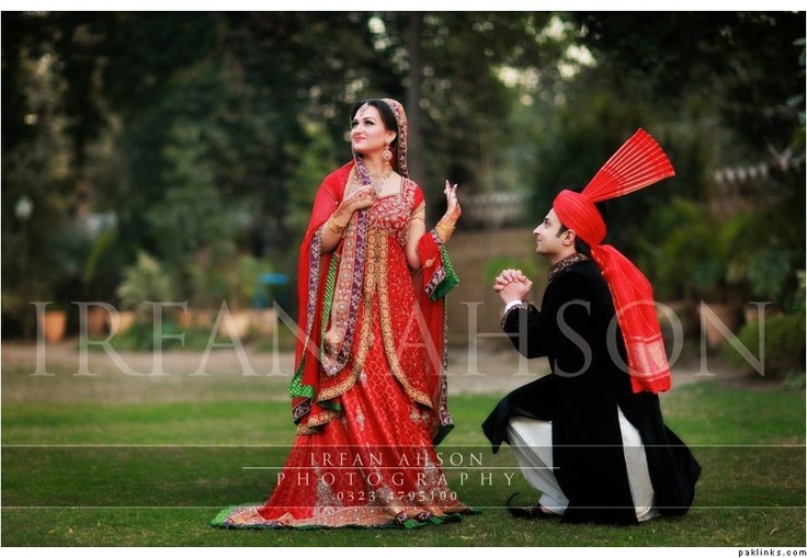 a man kneeling down next to a woman in a red dress