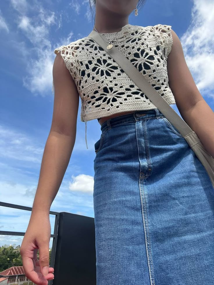 a woman wearing a white top and blue denim skirt is holding her hand out to the side