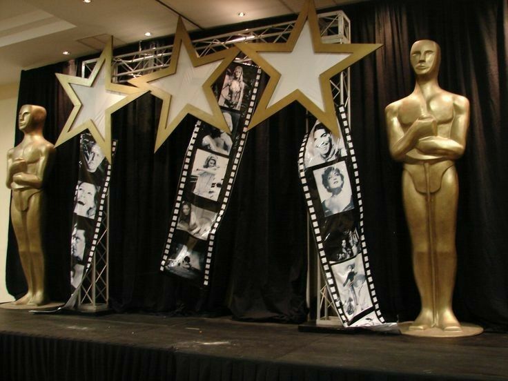 three oscar statues are lined up in front of black drapes with gold stars on them