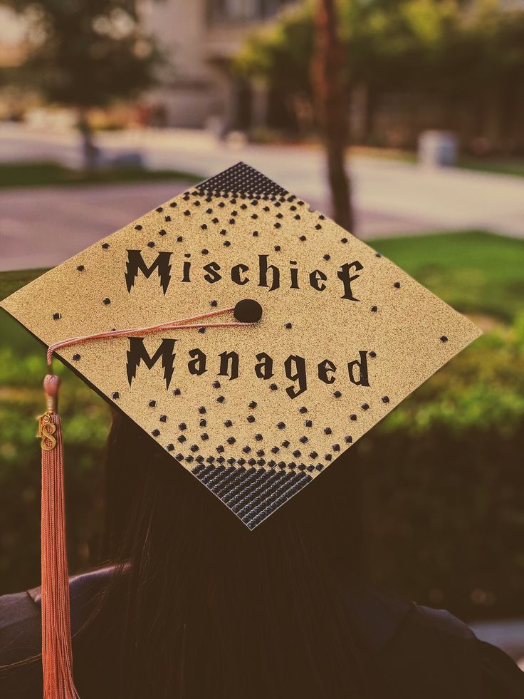 a person wearing a graduation cap with the words mischef managed written on it