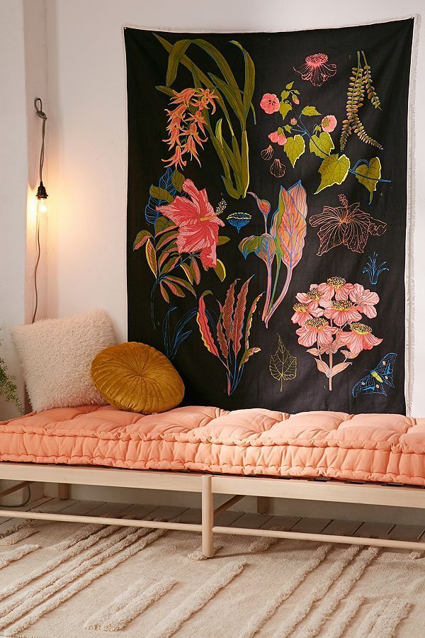 a room with a bed and a wall hanging on the wall, decorated with flowers