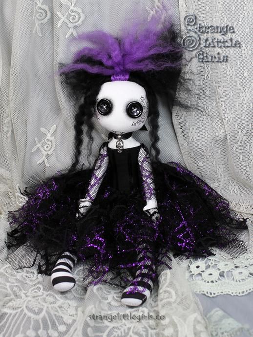 a doll with purple hair and black dress sitting on a lace doily covered surface