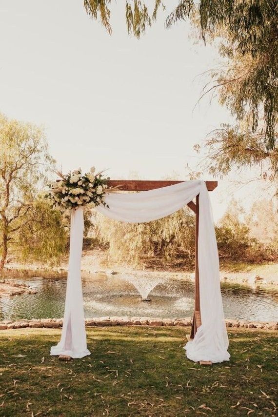 an outdoor wedding setup with white drapes and flowers