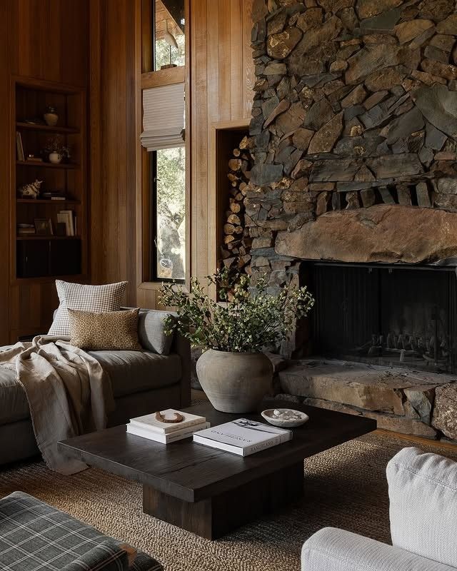 a living room filled with furniture and a fire place in front of a stone wall