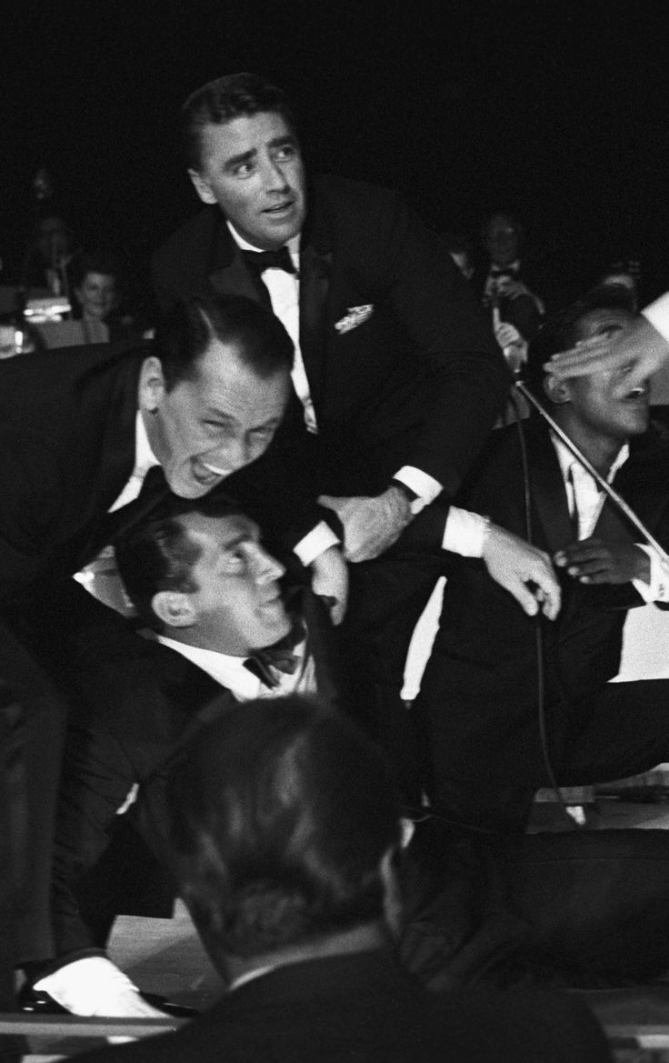 three men in tuxedos are pulling another man's suit over his shoulder