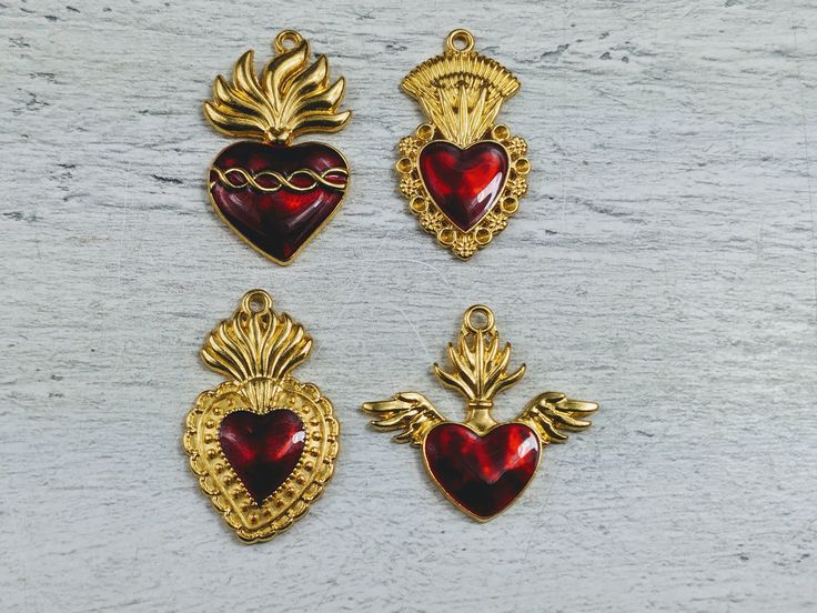 four heart shaped pendants with wings and hearts attached to each other on a white surface